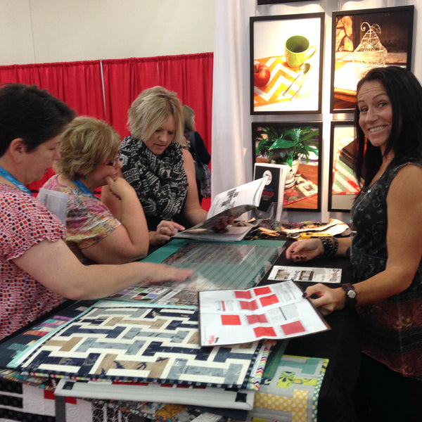 Gudrun Erla demonstrating a Stripology ruler to quilters at a trade show booth